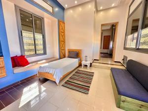 ein Schlafzimmer mit einem Bett, einem Sofa und Fenstern in der Unterkunft Du côté de chez Blili's in Al Matlīn