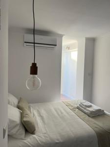- une chambre blanche avec un lit et un éclairage dans l'établissement AL44, à Beja