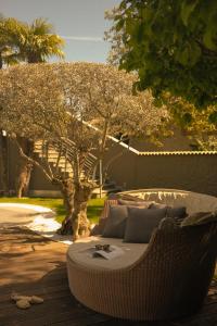 - un canapé en osier installé sur une terrasse en face d'un arbre dans l'établissement Hotel Mühlbacherhof, à Lagundo