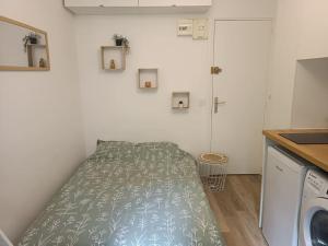 - une petite chambre avec un lit doté d'un couvre-lit vert dans l'établissement Studio à 35 min du cœur de Paris, à Saint-Cloud