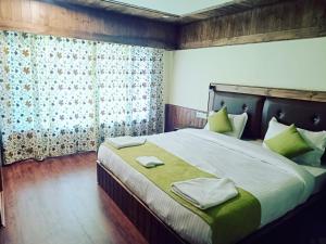 1 dormitorio con 1 cama grande con almohadas verdes en The Posh Residency, en Pahalgām