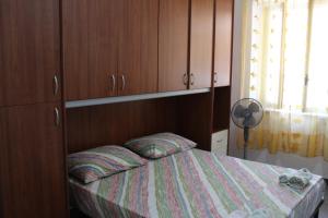 a small bedroom with a bed and wooden cabinets at Appartamento smart con splendido mare sotto casa in Capo Rizzuto