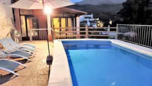 a pool with chairs and an umbrella next to a house at 5 bedrooms villa with private pool enclosed garden and wifi at Jerte in Jerte