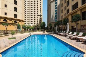 una gran piscina con tumbonas y edificios en Breathtaking Full Sea View Luxury Apartment JBR, en Dubái