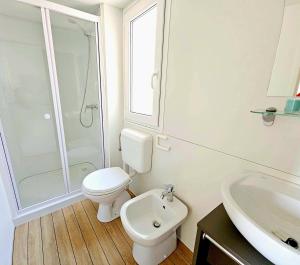 a white bathroom with a toilet and a sink at Villaggio Acquamarina in Pisciotta