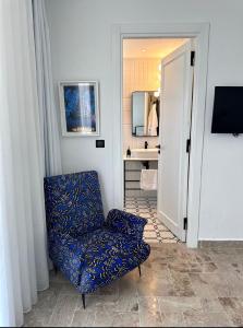 Cette chambre comprend une chaise bleue et une salle de bains. dans l'établissement Misk Villa - Boutique Hotel & Spa, à Sidi Bou Saïd