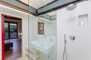 La salle de bains est pourvue d'un lavabo blanc et d'une douche. dans l'établissement Esclusivo loft con due camere da letto e terrazzo, à Milan