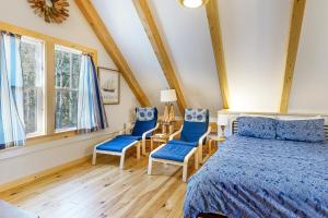 a bedroom with a bed and two blue chairs at Cooper Cottage in Boothbay Harbor