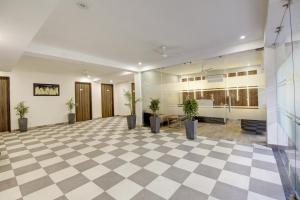 an empty lobby with potted plants on a checkered floor at Limewood Stay Golf Course Road in Gurgaon