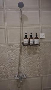 een douche met vier flessen op een plank in een badkamer bij Cozy one bedroom apartment in Riyad