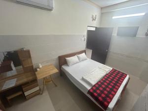 a small bedroom with a bed and a table at HOTEL ANH TUẤN in Ấp Cái Giá