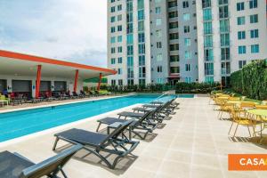 a pool with lounge chairs and tables and buildings at Hermoso apartamento a 15 minutos del aeropuerto in Heredia