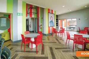 a restaurant with red chairs and tables and colorful walls at Hermoso apartamento a 15 minutos del aeropuerto in Heredia