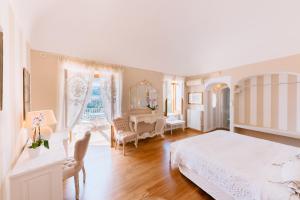 a white bedroom with a bed and a desk at Villa Mary Suites in Positano