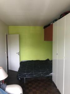 ein Schlafzimmer mit einem Bett und einer grünen Wand in der Unterkunft Appartement idéal JO in Maisons-Laffitte
