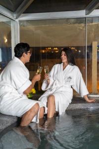 un hombre y una mujer sentados en el agua bebiendo champán en Hotel Jose Antonio Cusco, en Cusco