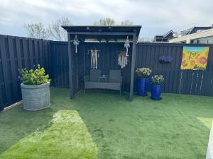 Un jardín con un cenador con una silla dentro. en De Gouwe Stek, en Landsmeer