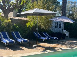 a group of chairs and an umbrella next to a pool at Chambre FLORENCE - MAS SAINT LOUIS in Aigues-Mortes