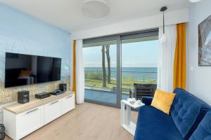 salon z niebieską kanapą i telewizorem z płaskim ekranem w obiekcie HS Apartamenty Hevenia Sun widok na morze w Rewalu