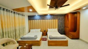 a bedroom with two beds and a ceiling fan at Hotel Sonar Bangla in Rāngāmāti