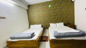 - 2 lits dans une chambre avec un mur dans l'établissement Hotel Sonar Bangla, à Rangamati