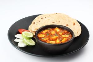 um prato preto com uma tigela de salsa e uma tortilla em OYO Samudra Executive em Pune