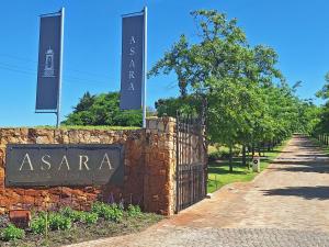 ein Schild an einer Ziegelmauer neben einem Zaun in der Unterkunft Asara Wine Estate & Hotel in Stellenbosch
