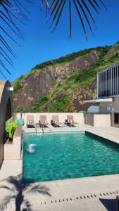 a swimming pool with chairs and a hill in the background at Mirador Rio Copacabana Hotel in Rio de Janeiro