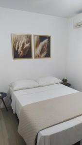 AP Confortável San Inácio في سانتو انجلو: سريرين في غرفة نوم مع صورتين على الحائط