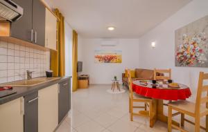 eine Küche und ein Wohnzimmer mit einem roten Tisch und Stühlen in der Unterkunft Apartments Kvarner in Malinska