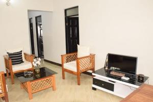 Two Bedrooms Apartment Moshi في Bunju: غرفة معيشة مع تلفزيون بشاشة مسطحة وكراسي