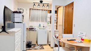 een keuken met een tafel en een witte koelkast bij E-REST ハウス瓦町 in Takamatsu