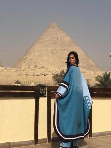a woman is standing in front of the pyramids at Pyramids Era View in Cairo