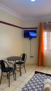uma sala de jantar com mesa e cadeiras e uma televisão em Studio room entebbe em Entebbe