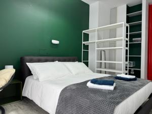 ein grünes Schlafzimmer mit einem Bett, auf dem Handtücher liegen in der Unterkunft Casa VM in Edolo