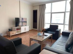 a living room with a couch and a tv at Blue Horizon Suites in Manama