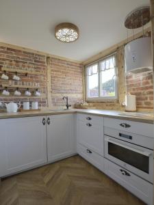 a kitchen with white cabinets and a brick wall at CENTRUM 47 KARPACZ in Karpacz
