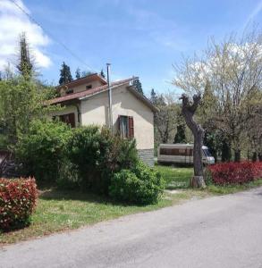 a house with a tree in front of a yard at Ostello di Pontito in Lanciole