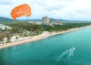 spadochron latający nad plażą z łodzią w wodzie w obiekcie Kalia Hotel w Duong Dong