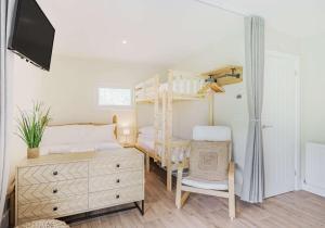a bedroom with a bunk bed and a dresser at Luxury Silver Birch Lodge: Hot Tub/BBQ/Fire Pit in Toppesfield