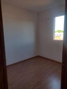 ein leeres Zimmer mit einem Fenster und einem Holzboden in der Unterkunft Manacá in Ribeirão Preto