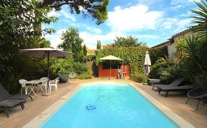 a swimming pool with a table and chairs and an umbrella at Chambre BELEM - Piscine chauffée - MAS SAINT LOUIS in Aigues-Mortes