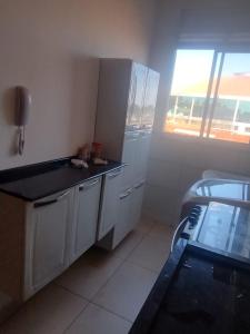 a kitchen with white cabinets and a black counter top at Manacá in Ribeirão Preto