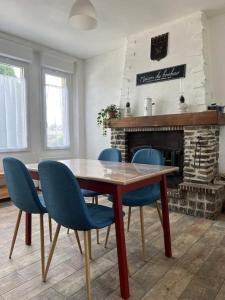 uma sala de jantar com uma mesa de madeira e cadeiras azuis em La Petite Maison em Lithaire