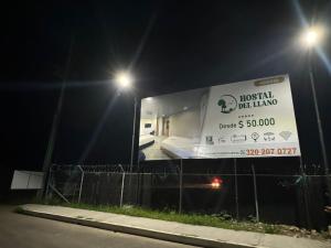 a sign for a hotel next to a street at night at HOSTAL DEL LLANO in Villavicencio