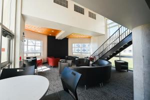 a lobby with tables and chairs and stairs at Residence & Conference Centre - Kingston in Kingston