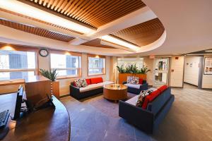 un hall de bureau avec des canapés, une table et une horloge dans l'établissement Residence & Conference Centre - Kingston, à Kingston