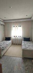 - 2 lits dans une chambre avec 2 fenêtres dans l'établissement Merveilleuse villa luxe privée, à Tunis