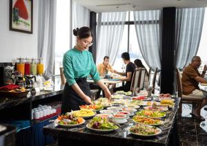 a woman standing in front of a table of food at Artisan Lakeview Hotel in Hanoi