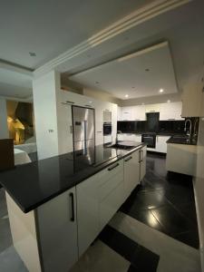 une cuisine avec des placards blancs et un comptoir noir dans l'établissement Merveilleuse villa luxe privée, à Tunis
